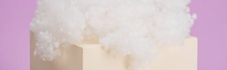 white fluffy cloud made of cotton wool on cube isolated on violet backgroundの写真素材