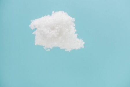 white fluffy cloud made of cotton wool isolated on blue backgroundの写真素材