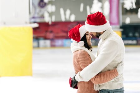 beautiful couple in santa hats spending time on skating rinkの写真素材