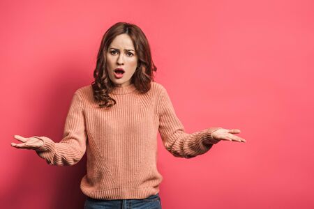 offended girl standing with open arms on pink background