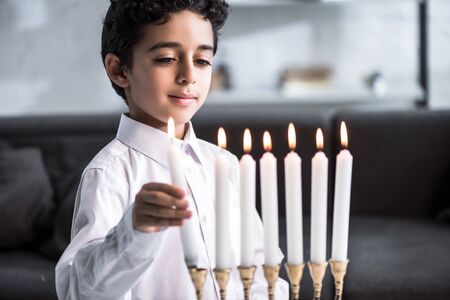 cute and smiling jewish boy in shirt holding candleの写真素材