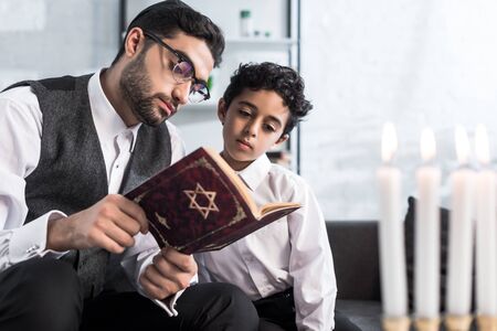 handsome jewish father and son reading tanakh in apartmentの写真素材