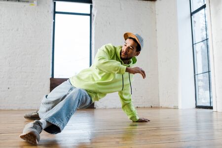 stylish african american man in cap breakdancing in dance studioの写真素材