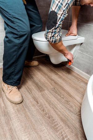 cropped view of man installing white toiletの写真素材