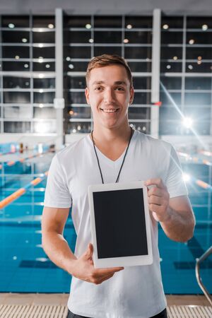 smiling trainer holding digital tablet with blank screenの写真素材