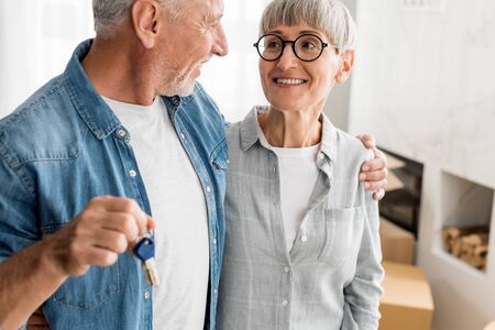 cropped view of smiling man holding keys and looking at woman in new houseの写真素材