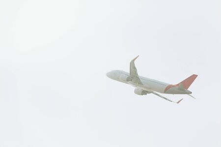 Low angle view of commercial plane taking off in cloudy skyの写真素材