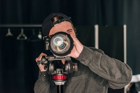 Videographer looking through camera while working in photo studioの写真素材
