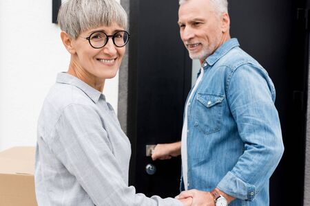 mature man looking at smiling woman and entering to new houseの写真素材