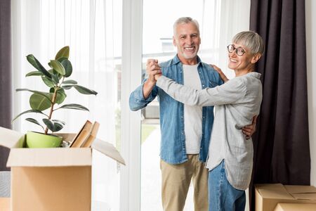 mature man and smiling woman dancing in new houseの写真素材