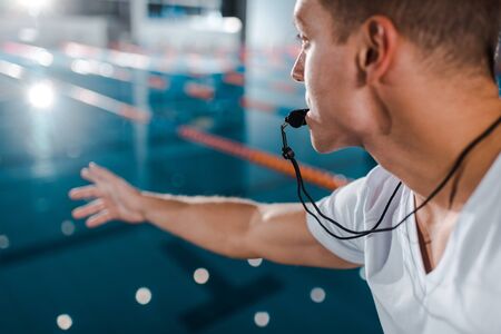 selective focus of trainer with whistle in mouth near swimming poolの写真素材
