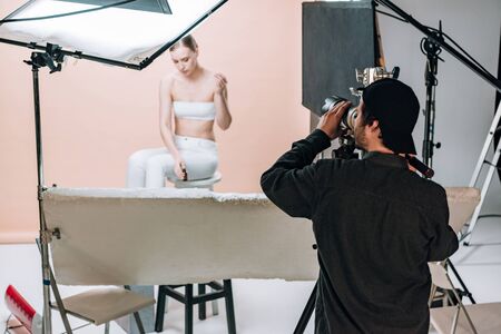Videographer with camera filming beautiful model in photo studio