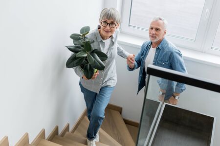 mature woman with plant holding hands with man in new houseの写真素材