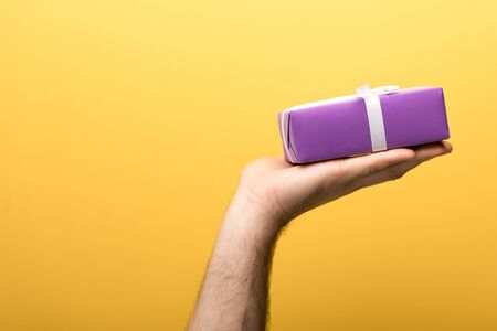 cropped view of man holding gift on yellow backgroundの写真素材