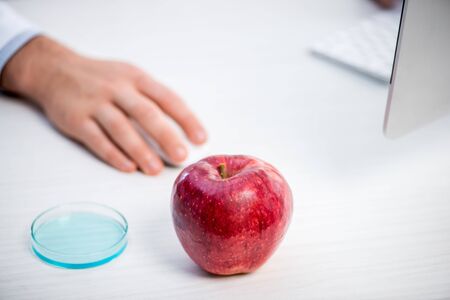 selective focus of ripe and fresh apple on table and molecular nutritionist on backgroundの写真素材