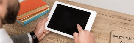 cropped view of businessman holding digital tablet with blank screen isolated on grey, panoramic...