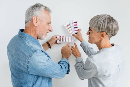 mature man and woman pointing with fingers at palette in new houseの写真素材
