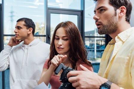selective focus of attractive art director gesturing near photographer and assistantの写真素材