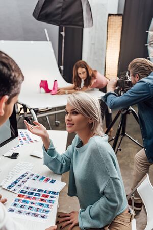 attractive art director gesturing and looking at assistantの写真素材