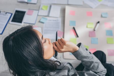 overhead view of asian scrum master touching face while thinking in office