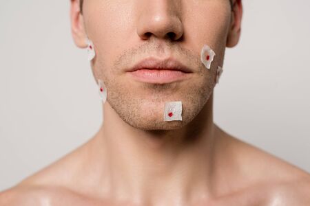 cropped view of naked man with bloody wounds after shaving on face isolated on greyの写真素材