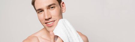 smiling sexy man with muscular torso holding cotton towel isolated on grey, panoramic shotの写真素材