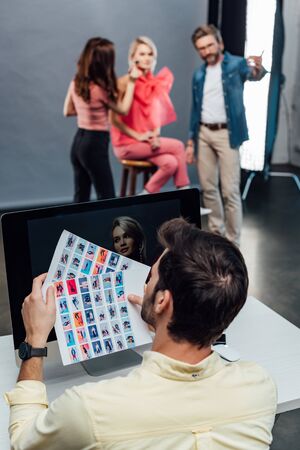 selective focus of art director holding photo collage near computer monitorの写真素材
