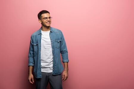 Handsome man smiling away on pink background with copy space