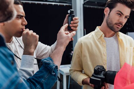 selective focus of man holding light meter near photographerの写真素材