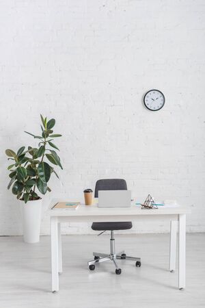 modern office with laptop on desk near brick wallの写真素材