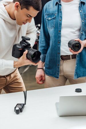 cropped view of art director holding photo lens near handsome photographerの写真素材