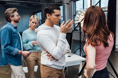 selective focus of man gesturing near art director and coworkers in photo studioの写真素材