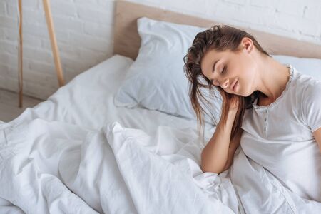 dreamy woman with closed eyes resting in bedの写真素材