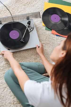 selective focus of vintage record player near girl sitting on carpet