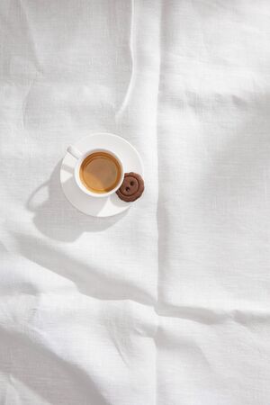 Top view of coffee cup with tasty cookie on white tablecloth with copy spaceの写真素材