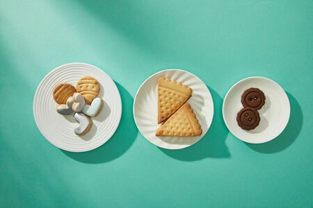 Top view of tasty cookies on plates on turquoise background