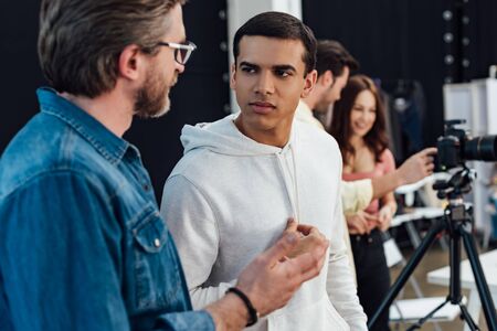 selective focus of handsome assistant looking at art director in glasses