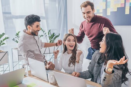 happy multicultural businessmen and businesswomen celebrating triumph in officeの写真素材