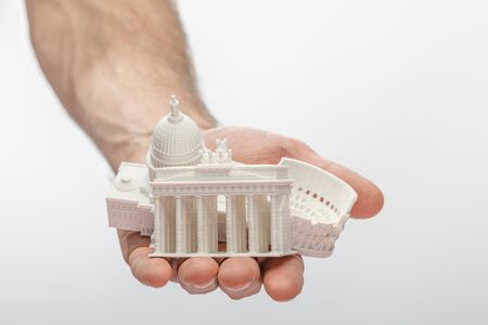 cropped view of man holding souvenirs from different countries isolated on whiteの写真素材