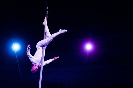 acrobat balancing on metallic pole in arena of circus