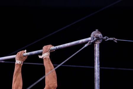 cropped view of athletic gymnast performing on horizontal bars in circusの写真素材