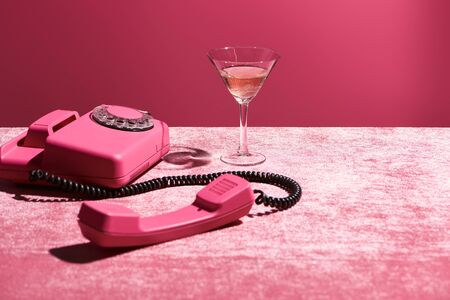 rose wine in glass near vintage phone on velour pink cloth isolated on pink, girlish conceptの写真素材