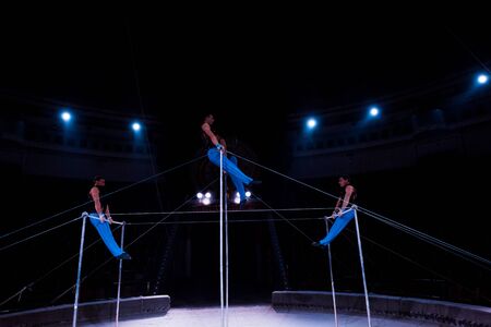 handsome acrobats performing on horizontal bars in circusの写真素材