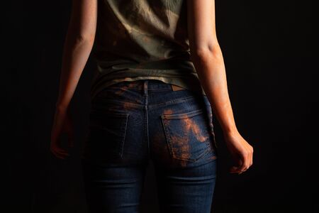 back view of woman with orange colorful holi paint powder on clothes on black backgroundの写真素材