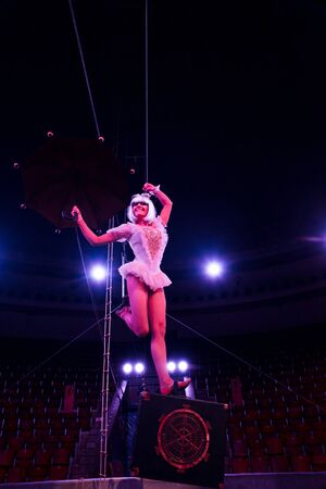 artistic aerial acrobat holding umbrella while performing in circusの写真素材