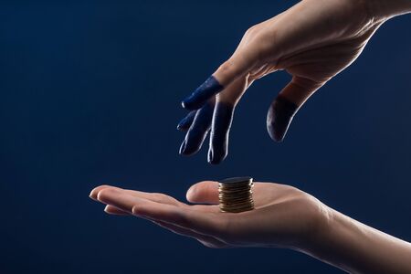 cropped view of female hand with painted fingers holding coins isolated on blueの写真素材