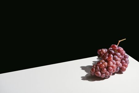 classic still life with grape with shadow on white table isolated on blackの写真素材