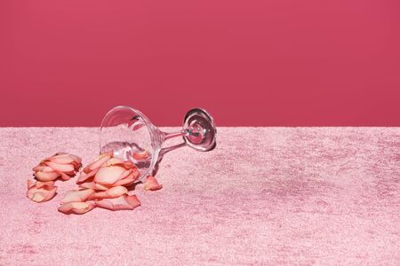 rose petals near glass on velour pink cloth isolated on pink, girlish conceptの写真素材