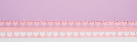 top view of pink, violet paper with cut out hearts on white background, panoramic shotの写真素材
