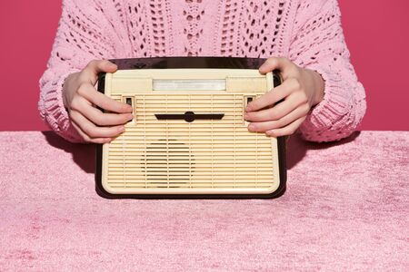 cropped view of woman holding vintage radio on velour cloth isolated on pink, girlish conceptの写真素材